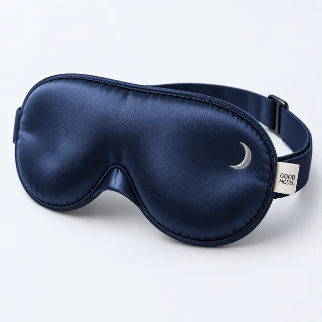 Midnight-blue padded sleep mask with a small silver crescent stitched on the front